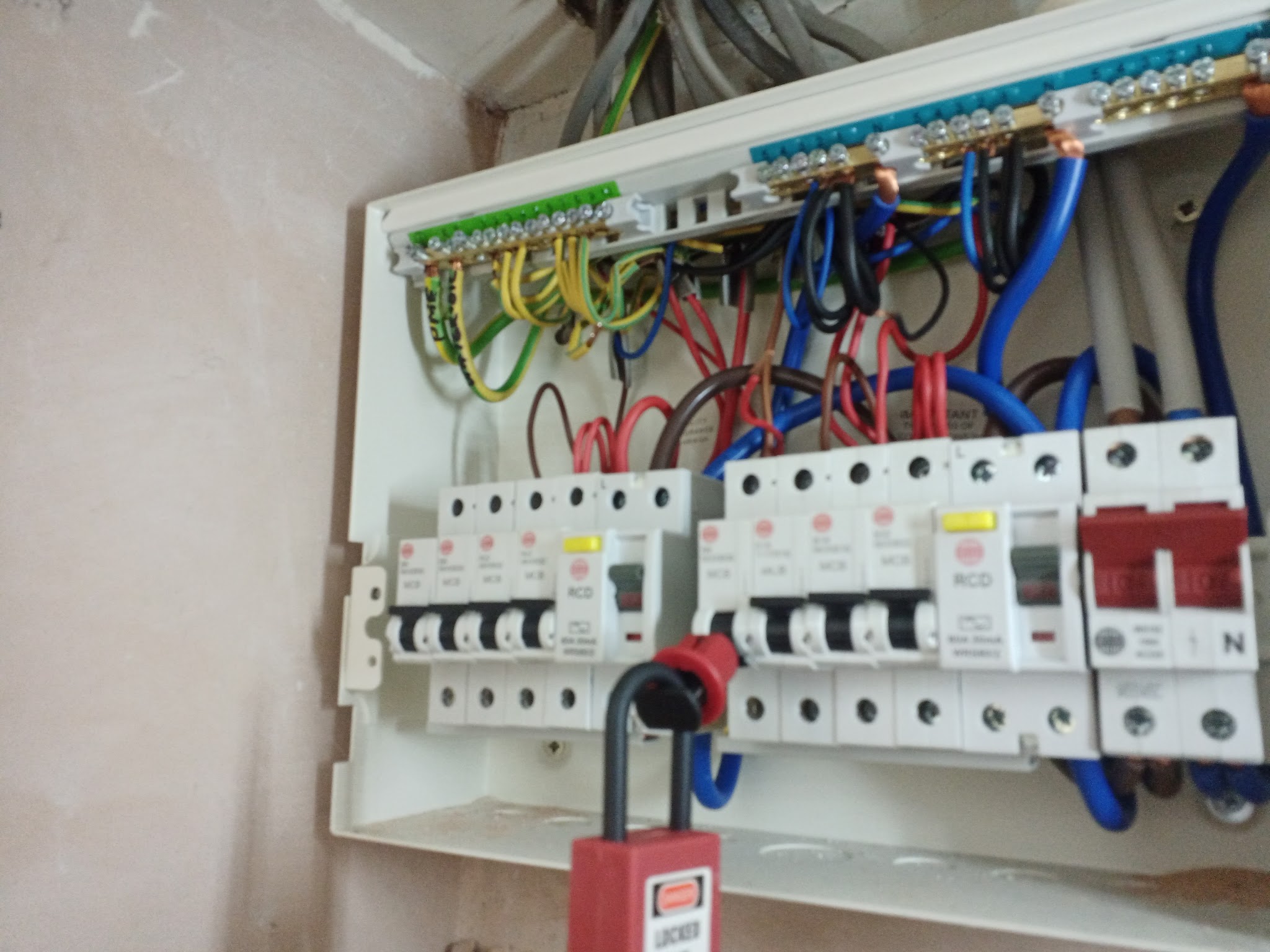 A new consumer unit with its cover off, locked off with a red safety padlock