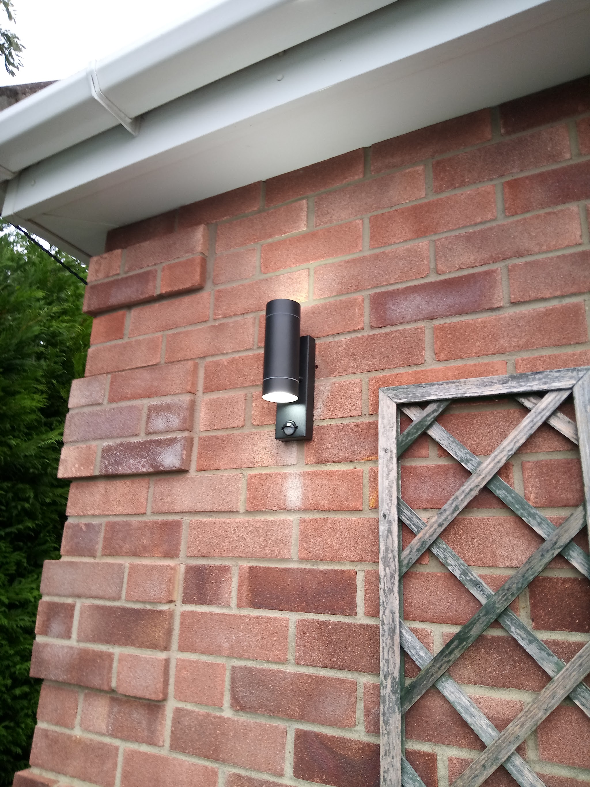 A new black outdoor wall light fitted to a brick wall